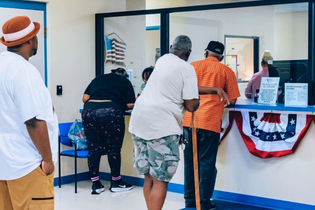 RB Banks (at desk in orange shirt) of the Alachua Nine registers to vote after the Florida Rights Restoration Coalition pays his fines. Courtesy of Florida Rights Restoration Coalition