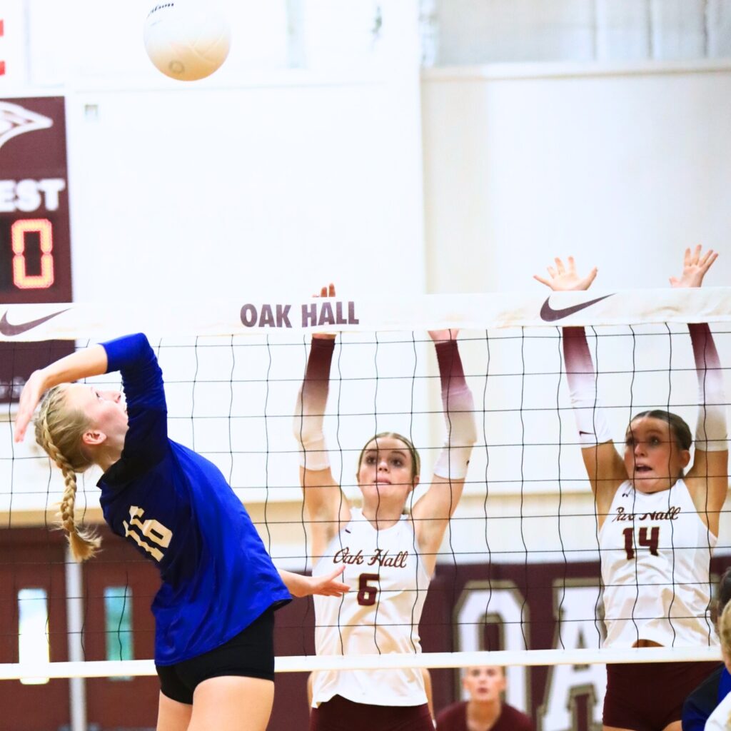 Saint Francis Catholic's Hailey Schoster (16) with a hit against Oak Hall's Hannah Timm (6) and Kendylle Bishop (14). Photo by C.J. Gish 1 (1)