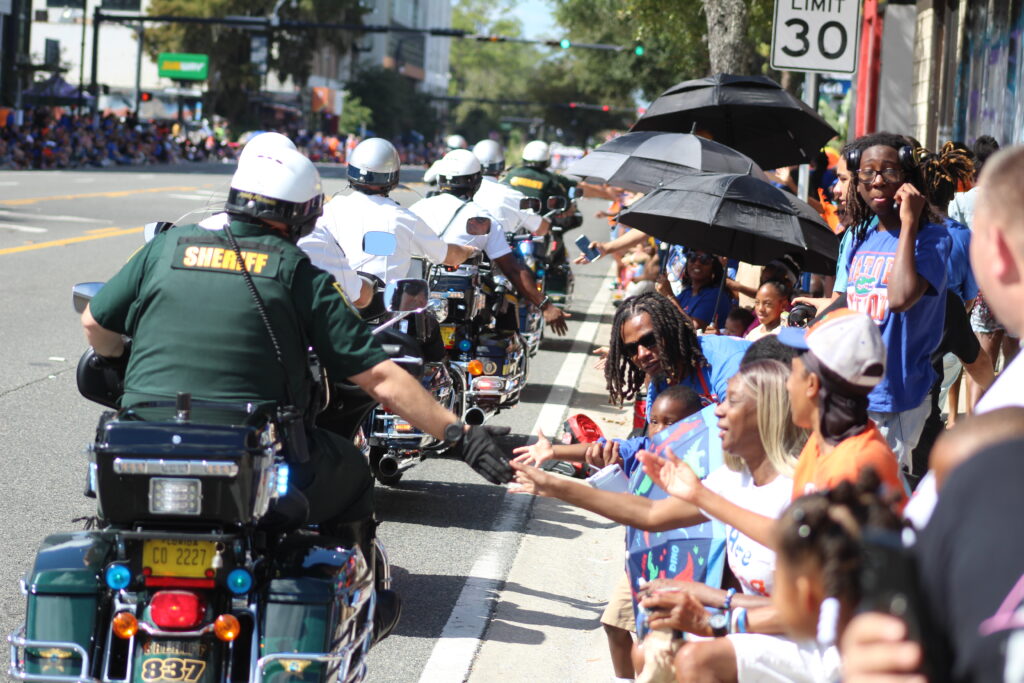 The Alachua County Sheriff's Office (ACSO) Motor Unit high fives spectators during the UF Homecoming Parade