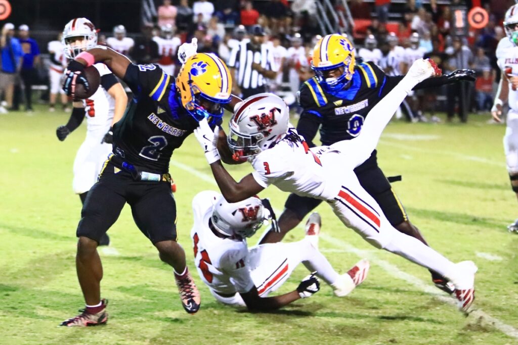 Williston's Kyrin Penny (3) grabs the facemask of Newberry's Kaleb Woods (2) on a second-quarter run. Photo by C.J. Gish
