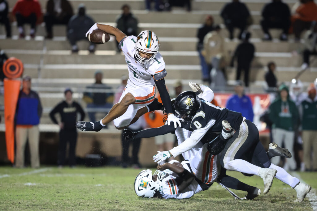Mandarin's Brysen Wright (1) jumps a tackle by Buchholz player Amir Sheppard (0) during the first half of Friday's playoff tilt at Citizens Field in Gainesville. 