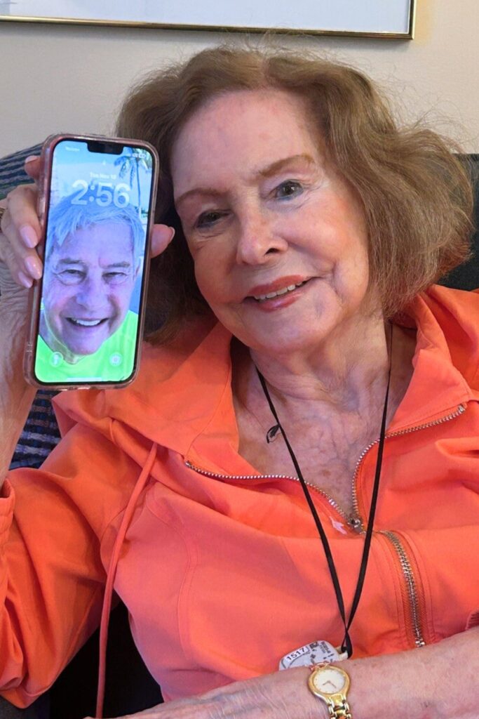 Adele Graham takes out her phone with her screensaver of her late husband, Governor Bob Graham. Photo by Ronnie Lovler