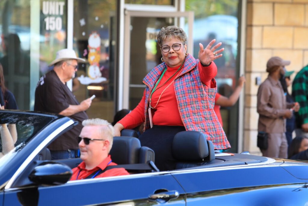 Commissioner Cynthia Chestnut, who pushed to restart the city parade, greets attendees from atop a convertible. Photo by Seth Johnson
