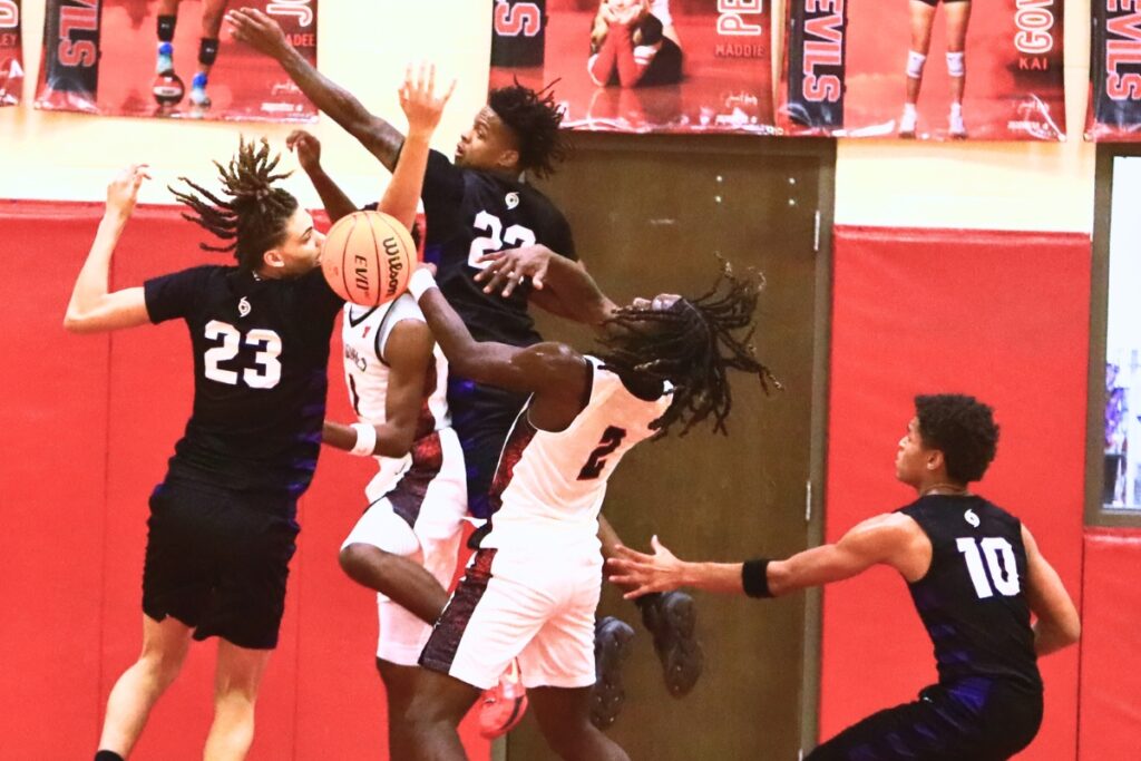 Gainesville and Williston players go after a loose ball after a missed shot. Photo by C.J. Gish