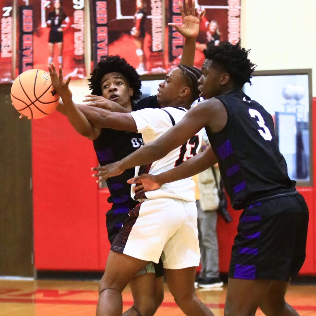 Gainesville's Anthony Jenkins Jr. (20) and Corvaughn White (3) sandwich Williston's Todd Brown (13) on defense. Photo by C.J. Gish