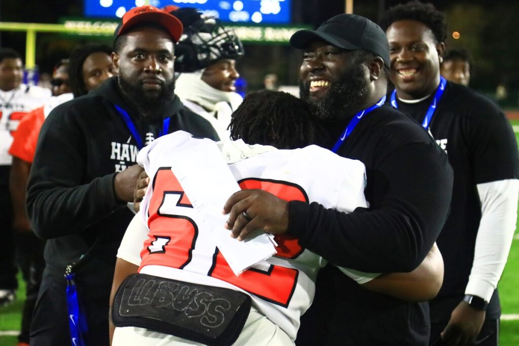 Hawthorne offensive coordinator Greg Bowie embraces Tellis Harris (62) after the Hornets' win against Blountstown in the FHSAA Rural State Championship game. Photo by C.J. Gish 1 (1)