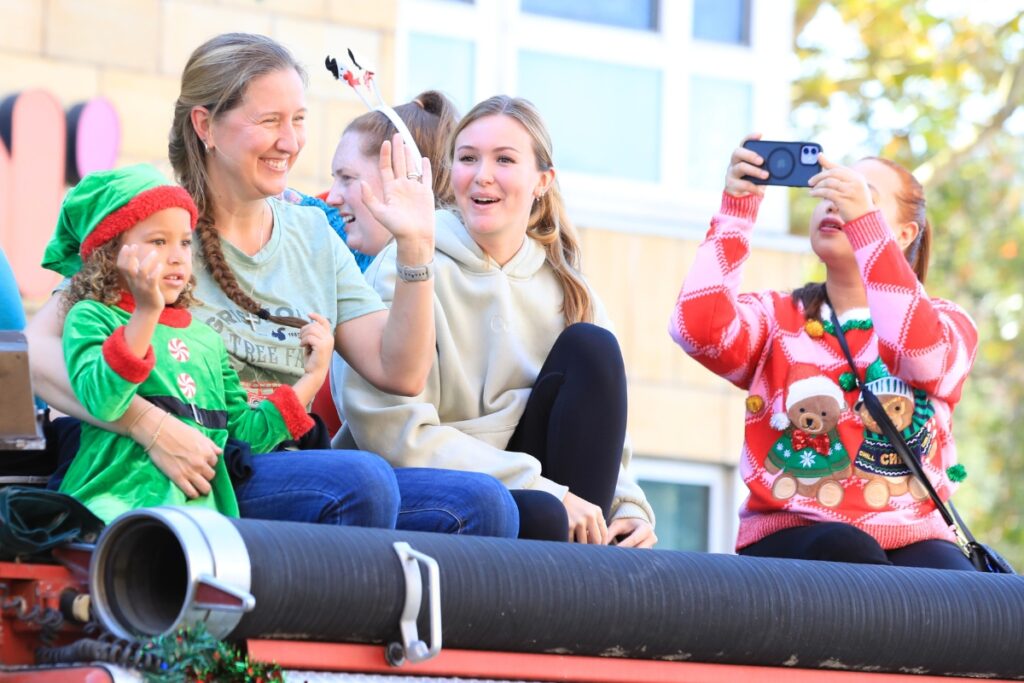 Sitting atop a vintage fire truck, parade attendees wave. Photo by Seth Johnson