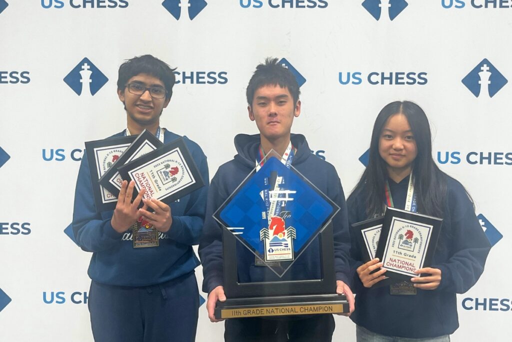 The Frazer School's 11th-grade chess team hold trophies after winning first place at the US Chess Federation’s National K-12 Grade Championships.