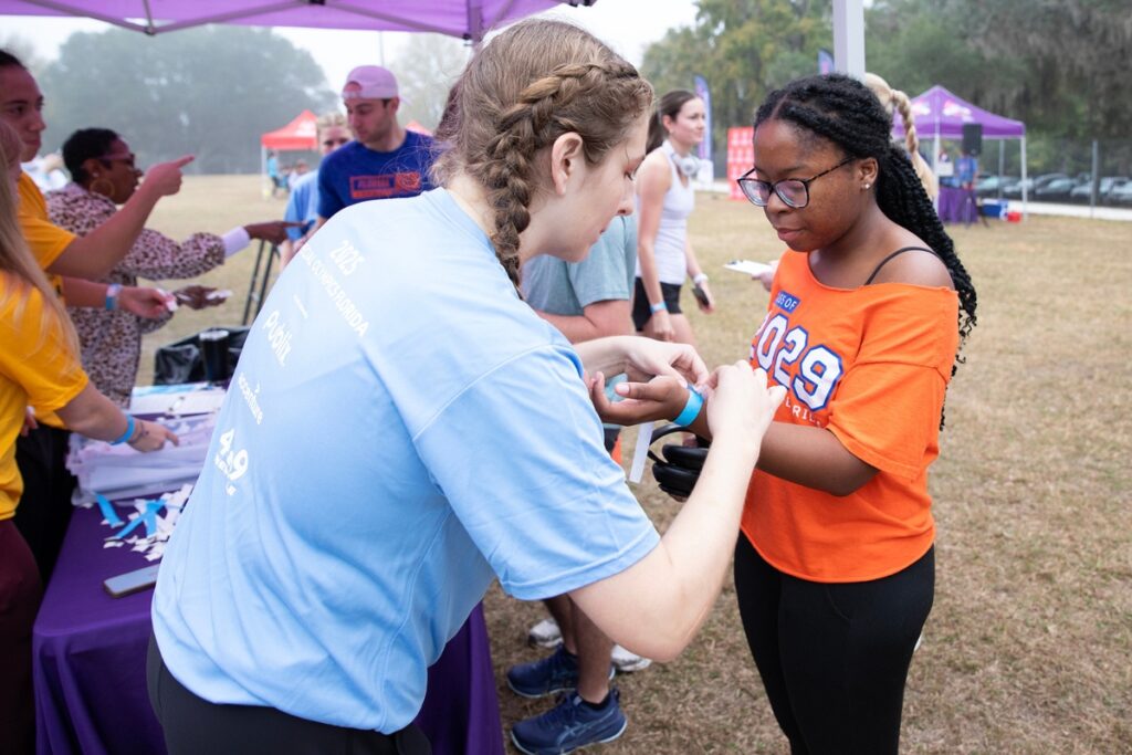 Volunteer Mary Reimann, vice president of programming for UF Special Olympics, attaches an arm band for a race participant. Photo by Megan V. Winlsow