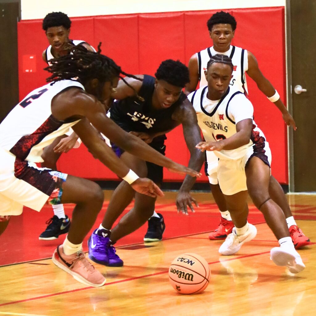 Williston's Jaden Magee (2) and Todd Brown (13) and Gainesville's Antonio Hall (44) go after a loose ball. Photo by C.J. Gish