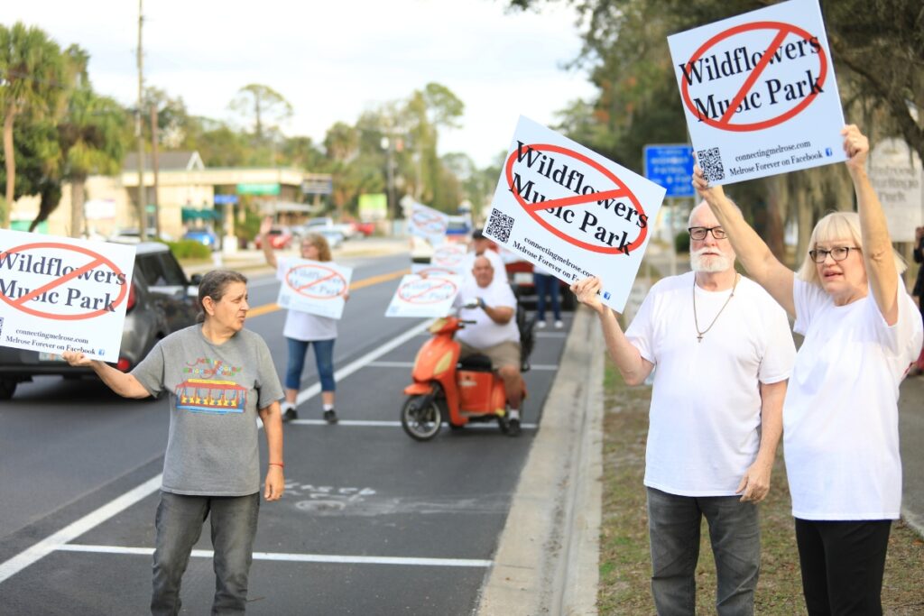 Melrose residents hold signs along SR 26 to protest the temporary use permit for the WildFlowers Music Park.