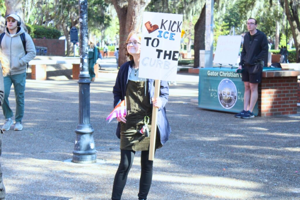 Alex Lawson holds an anti-ICE sign in Turlington Plaza on Friday. Photo by Nick Anschultz
