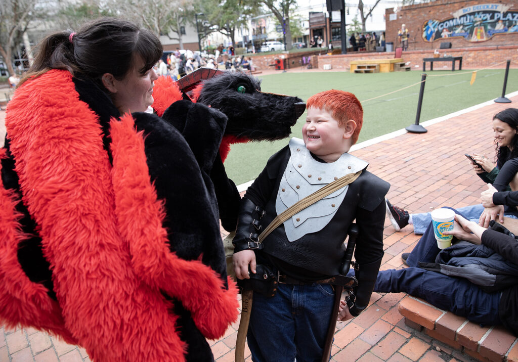 Ashley Ladnyk, also known as “Brigit the Blacksmith,” and Ember the Forge Dragon charm Bob Lofstrom, 8, during a performance break Saturday.