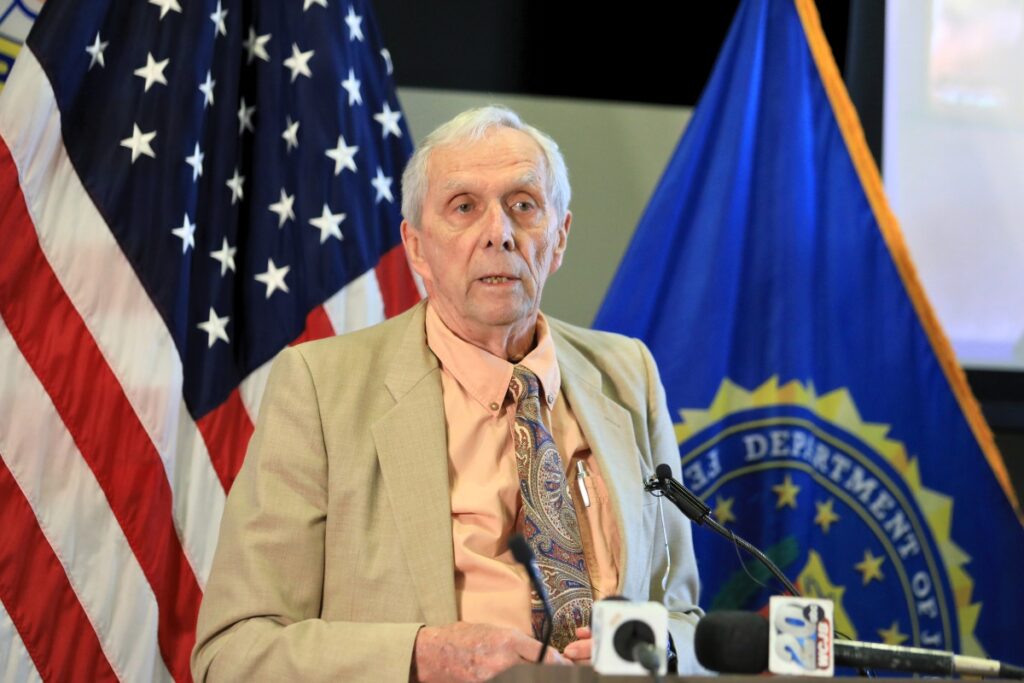 Brian Oliver speaks from a podium to talk about the fraud scheme that resulted in losing $200,000.