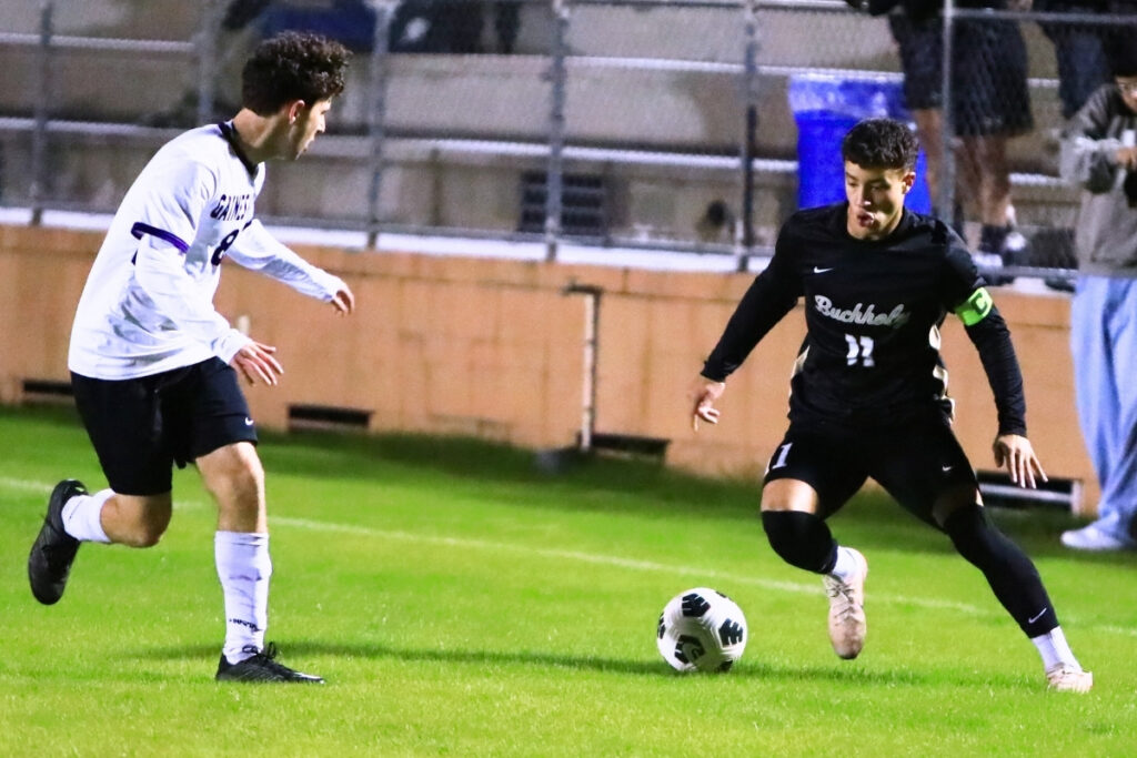 Buchholz's Carlos Cadet (11) brings the ball downfield against Gainesville's Antonious Khalil (8). Photo by C.J. Gish