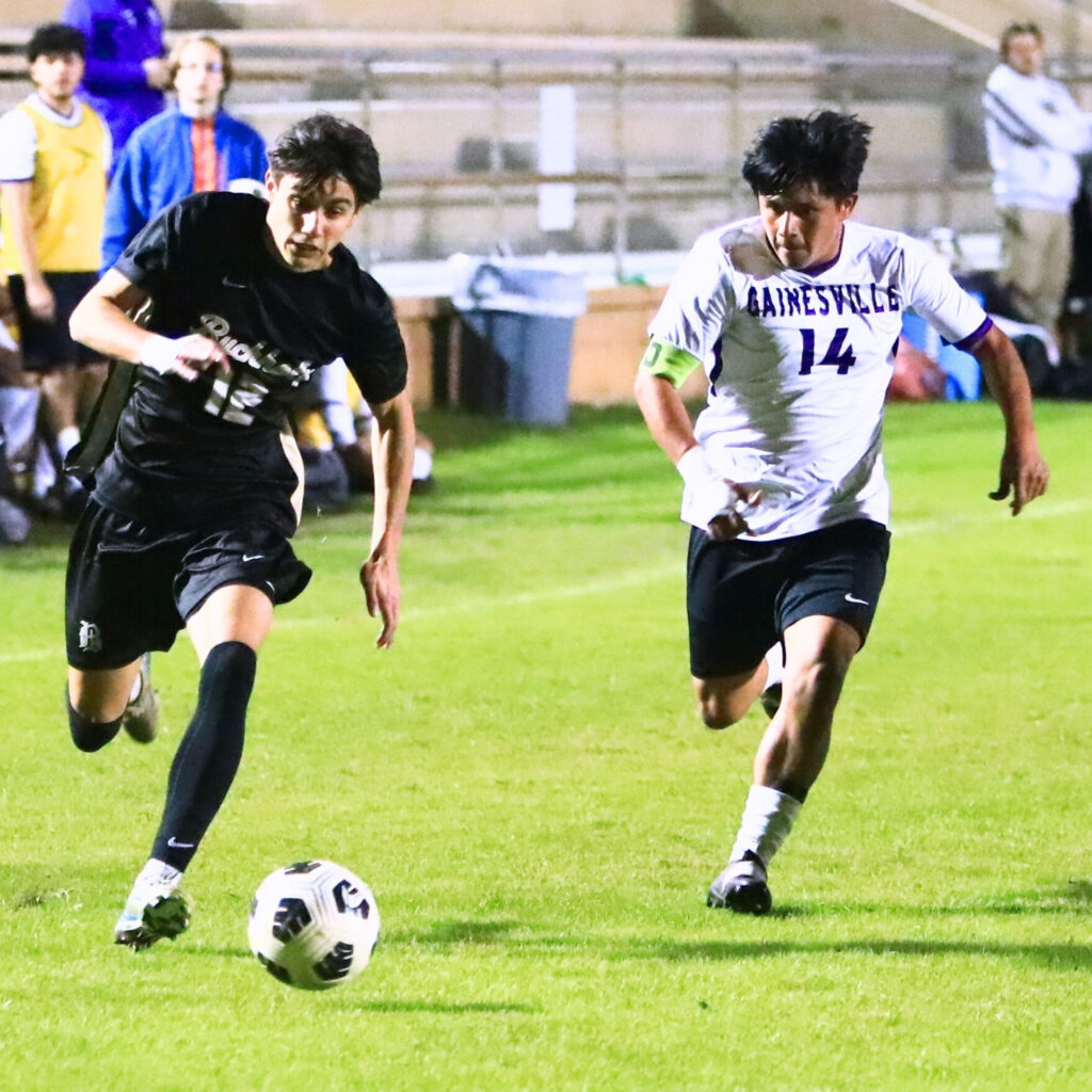Buchholz's Christian McDaniel (12) brings the ball downfield with Gainesville's Edson Maquin (14) in pursuit. Photo by C.J. Gish