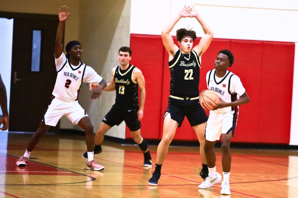 Buchholz's Evan Walker (22) defends Williston's Kyson Chever (11). Photo by C.J. Gish