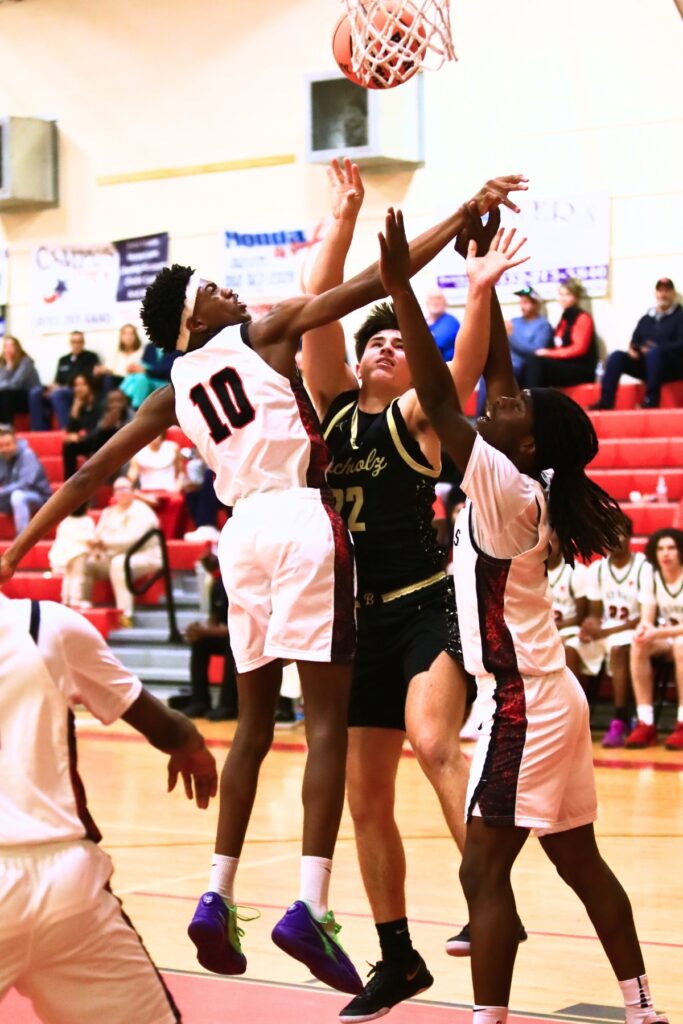 Buchholz's Evan Walker (22) gets fouled on a shot against Williston's Malachi Fernandez (10) and Jaden Magee (2). Photo by C.J. Gish
