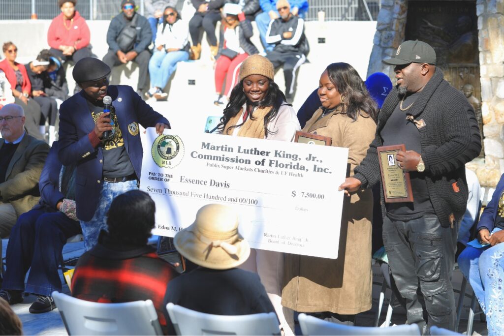 Essence Davis (center) receives a check as the winner of the Edna M. Hart Keeper of the Dream Award.