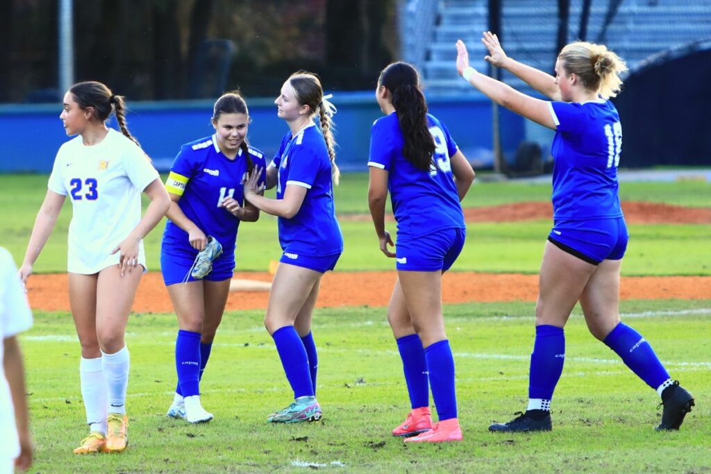 P.K. Yonge's Paulina Cervantes (11) celebrates with teammates after losing her shoe while kicking the game's first goal for a 1-0 lead against Newberry. Photo by C.J. Gish
