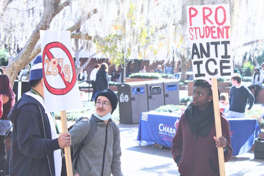 Protesters hold anti-ICE signs in Turlington Plaza on Friday. Photo by Nick Anschultz