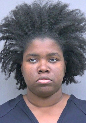 Trinity Johnson. Black woman with lots of hair in prison outfit.