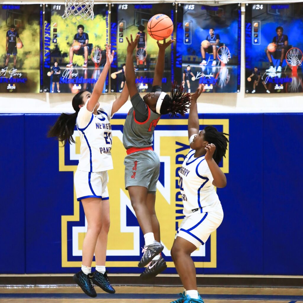 Williston's Janiyah Span (14) puts up a shot between Newberry's Kaya Troche (21) and Jada Brown (30). Photo by C.J. Gish