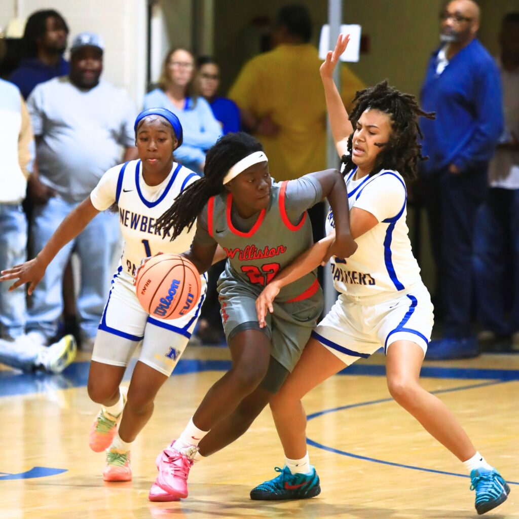 Williston's Kaelynn Brown (22) tries to get around Newberry's Rihanna Chiever (3). Photo by C.J. Gish