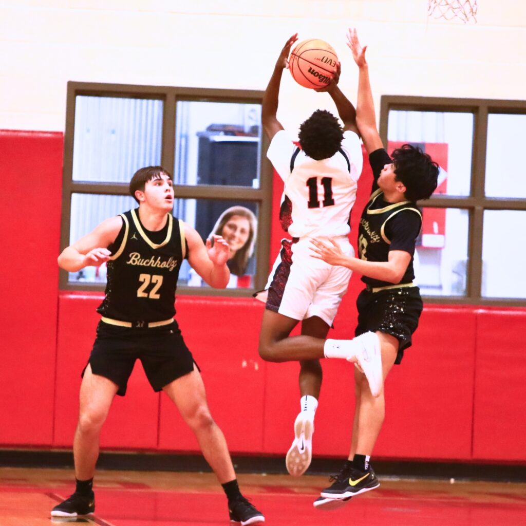 Williston's Kyson Chever (16) puts up a shot against Buchholz's Ezra Olmedo (12). Photo by C.J. Gish