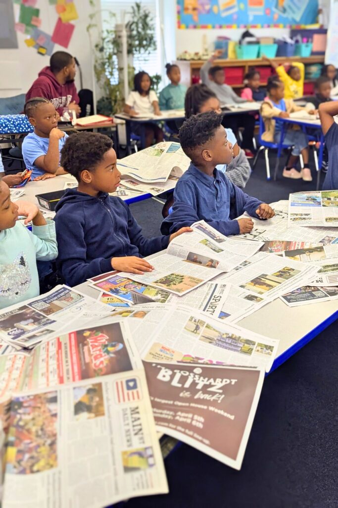 (From left in front row) Second graders Sophie Duggins, Oliver Tulloch, Kenzy Miller, Makhi Minor practice literacy skills with Mainstreet Daily News print editions.