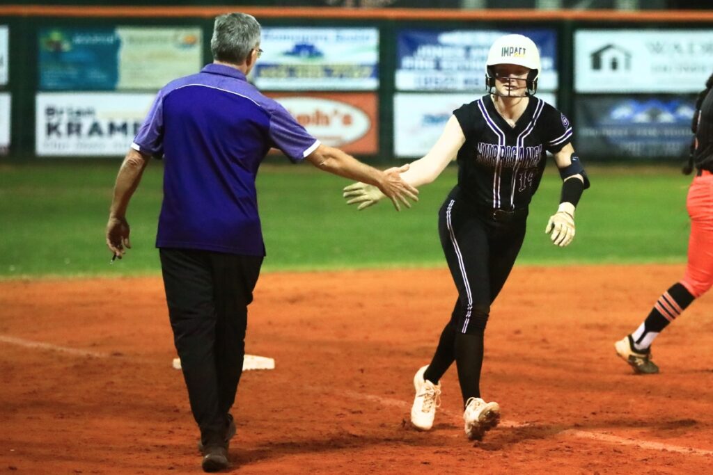 Gainesville's Leanna Bourdage (14) gets a high-five from coach Chris Chronister after hitting a solo home run in the top of the fourth inning against Trenton. Photo by C.J. Gish