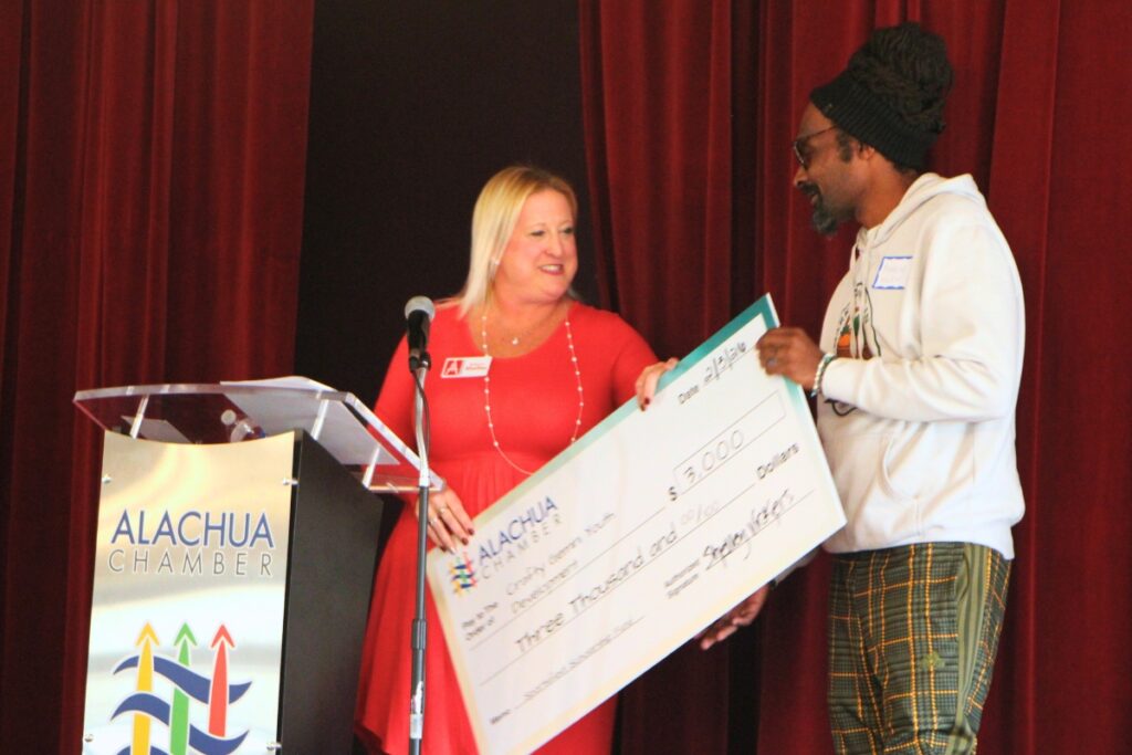 Shelley Vickers (left) presents Crafty Gemini founder Brandon Wilson (right) with a $3,000 check from the Alachua Chamber of Commerce. Photo by Lillian Hamman