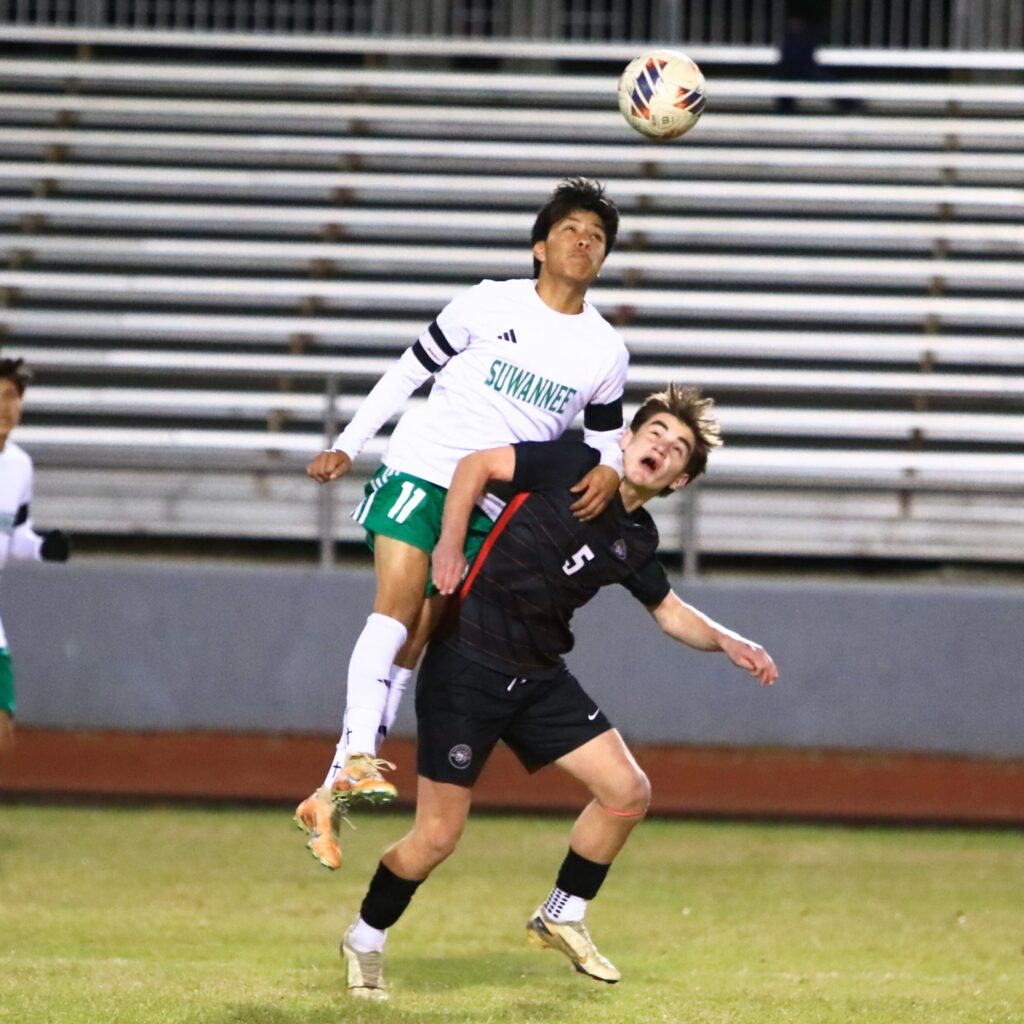 Suwanne's Scott Uribe (11) climbs over Santa Fe's Owen Boone (5) to get the ball in the Class 3A-Region 1 Quarterfinals. Photo by C.J. Gish