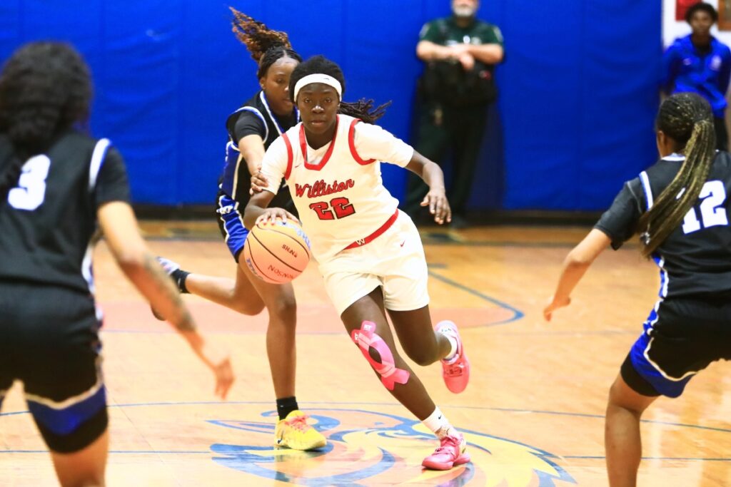 Williston's Kaelynn Brown (22) drives through Wildwood defenders in the Rural Class District 7 championship game. Photo by C.J. Gish