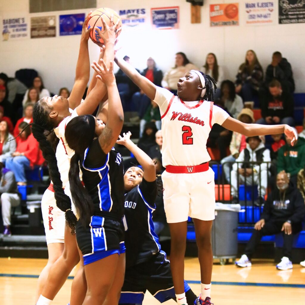 Williston's Tiona Wilkinson (4) and Trinity Solomon (2) battle for a rebound against Wildwood in the Rural Class District 7 championship game. Photo by C.J. Gish