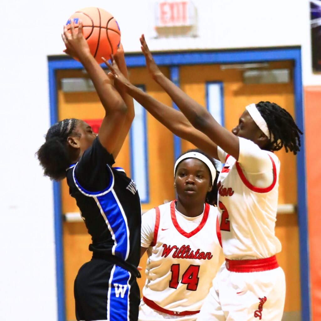 Williston's Trinity Solomon (2) and Janiyah Spain (14) with a defensive trap against Wildwood in the Rural Class District 7 championship game. Photo by C.J. Gish