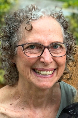 Janice Garry. Woman with curly hair and glasses