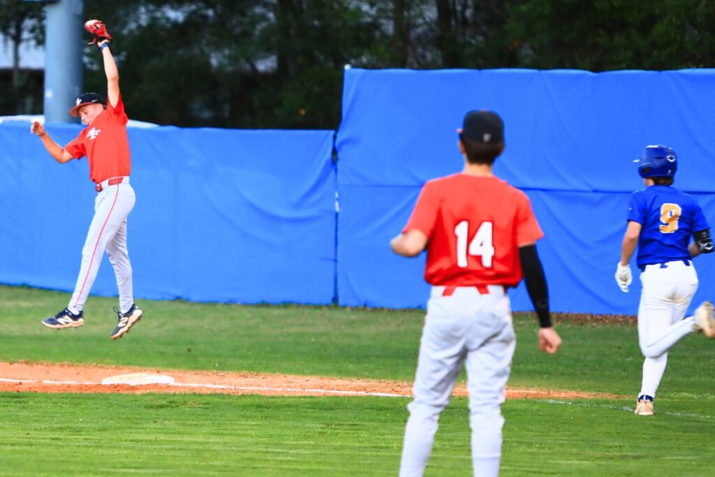 Santa Fe first baseman Cole Crevasse (7) leaps into the air to snag a throw to get Newberry's Cameron Burford (9) out. Photo by C.J. Gish
