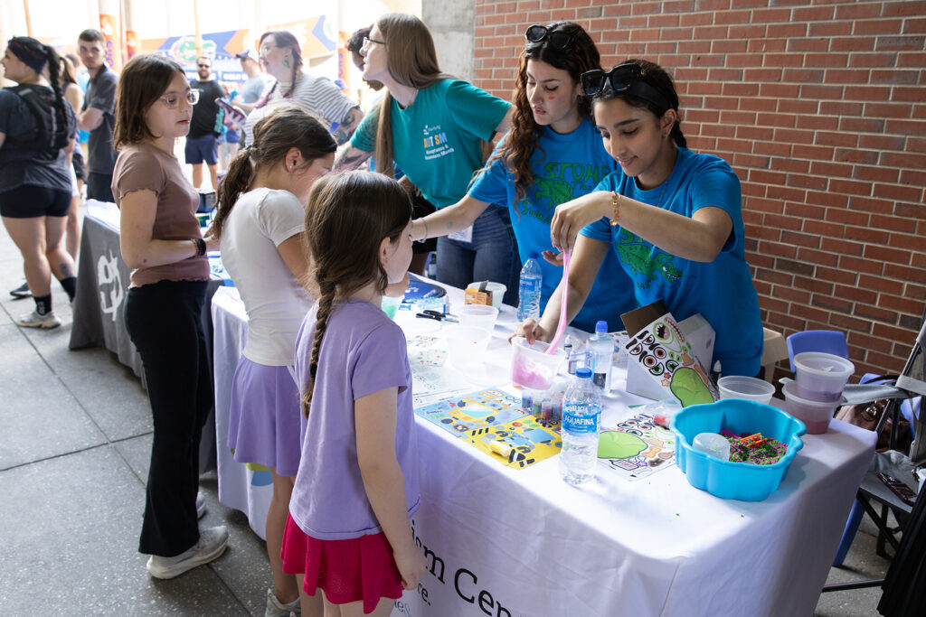 Stomp the Swamp volunteers help children make “slime.” Photo by Megan V. Winslow