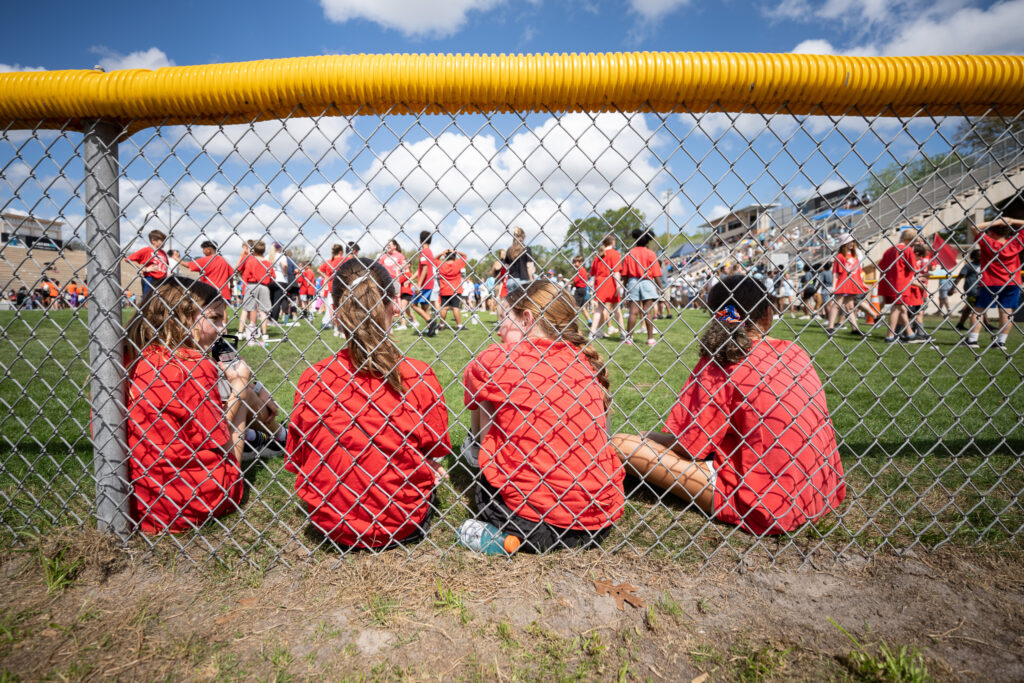 Students from High Springs Community School sit against the fence after racing in the relay race.
