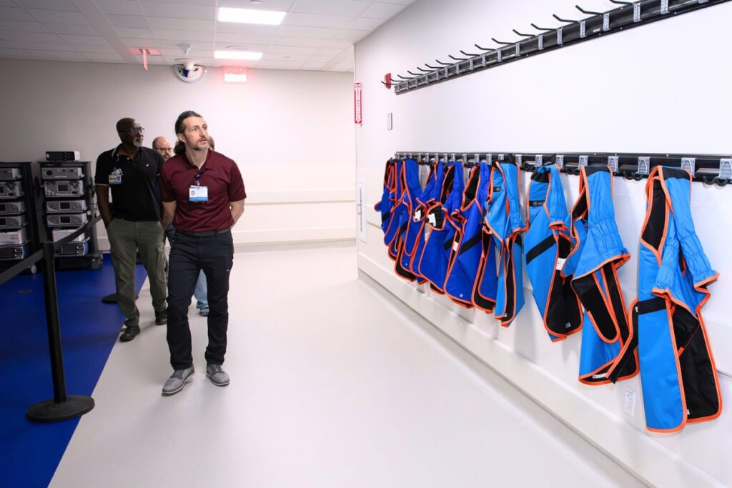 UF Health clinical engineers examine a wall of weighted vests used to protect patients undergoing X-rays. Photo by Megan V. Winslow