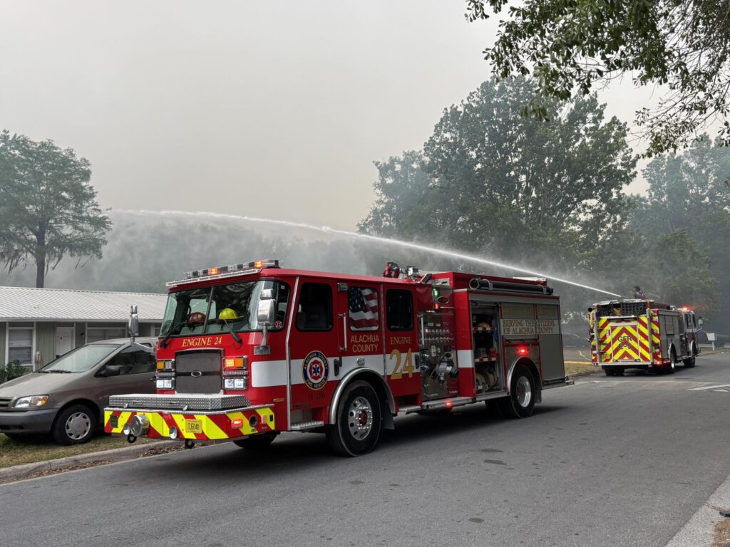 Alachua County Fire Rescue sprays water over a house after a wildfire started on the north side of Gainesville.
