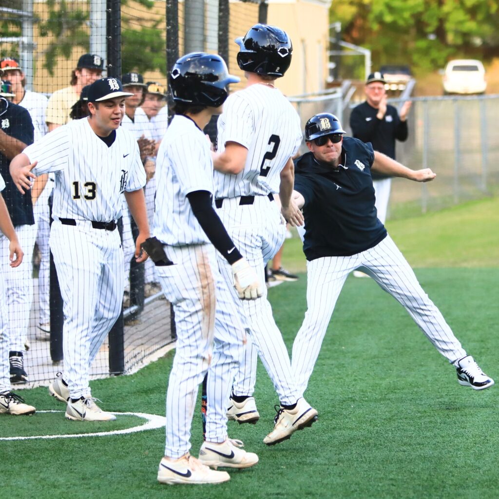 Buchholz coach Chris Malphurs (right) congratulates Aidan Kastensmidt (2) after Kastensmidt stole home for a 5-2 first inning lead against Mandarin (Jacksonville) in the 5A-Region 1 Quarterfinals.