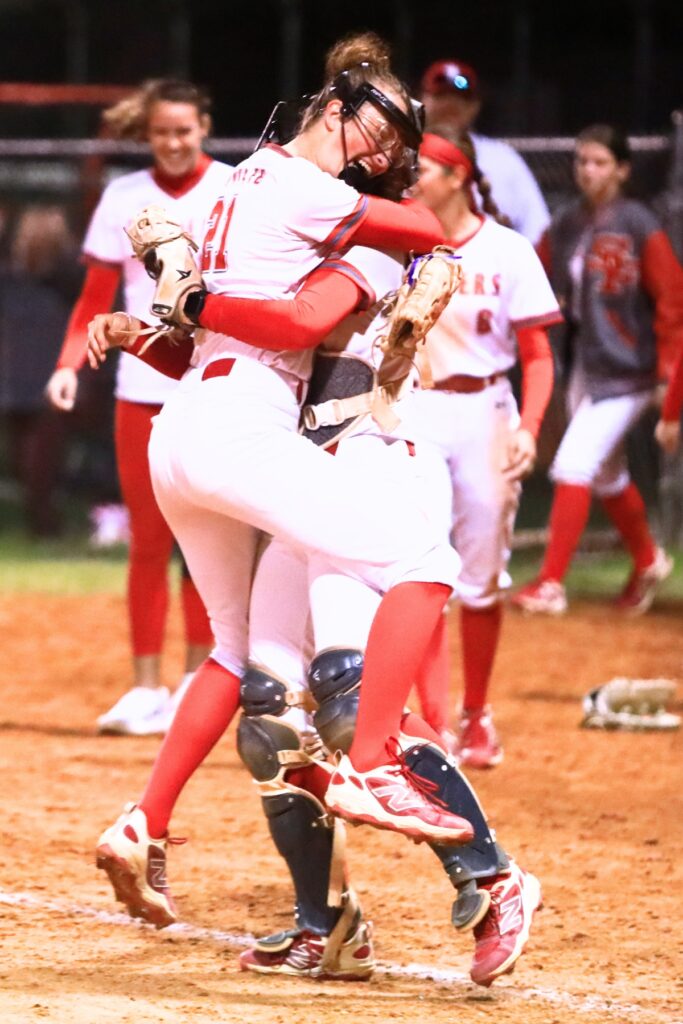 Santa Fe pitcher Ryleigh Davis (21) jumps into the arms of catcher Ainslea Kelsoe after throwing the final strikeout in a 3-2 home win over Trenton. Photo by C.J. Gish