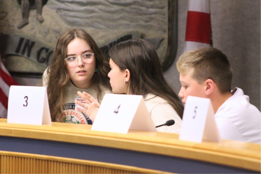 Students huddle to discuss an answer. Photo by Nick Anschultz