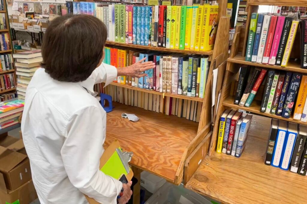 Sue Morris browses the Friends of the Library shelves for a Carl Hiaasen book.