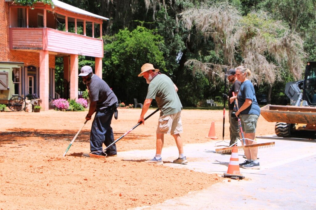 Crews rake six truckloads of red clay across NE 1st Street in Micanopy. Photo by Lillian Hamman