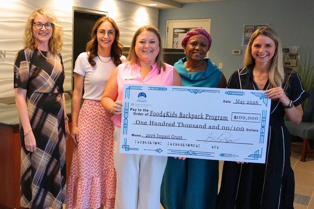 Food 4 Kids Executive Director Margot DeConna (center) receives a $100,000 commemorative check from Community Foundation and Women's Giving Circle representatives.