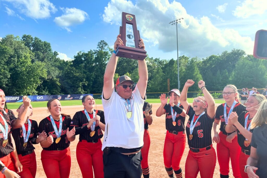 Trenton coach Kevin Benson lifts up the FHSAA Rural state championship softball trophy. Photo by Mike Ridaught
