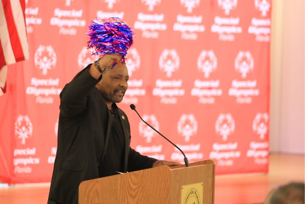 Alachua Sheriff Chad Scott waves a pompom as he encouraged the athletes and coaches ahead of their departure.